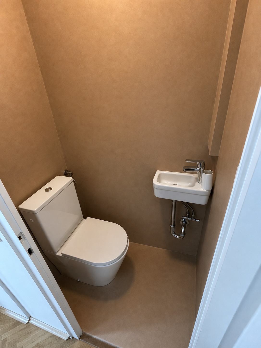 Rjav dekor cement v WC prostoru z manjšim umivalnikom