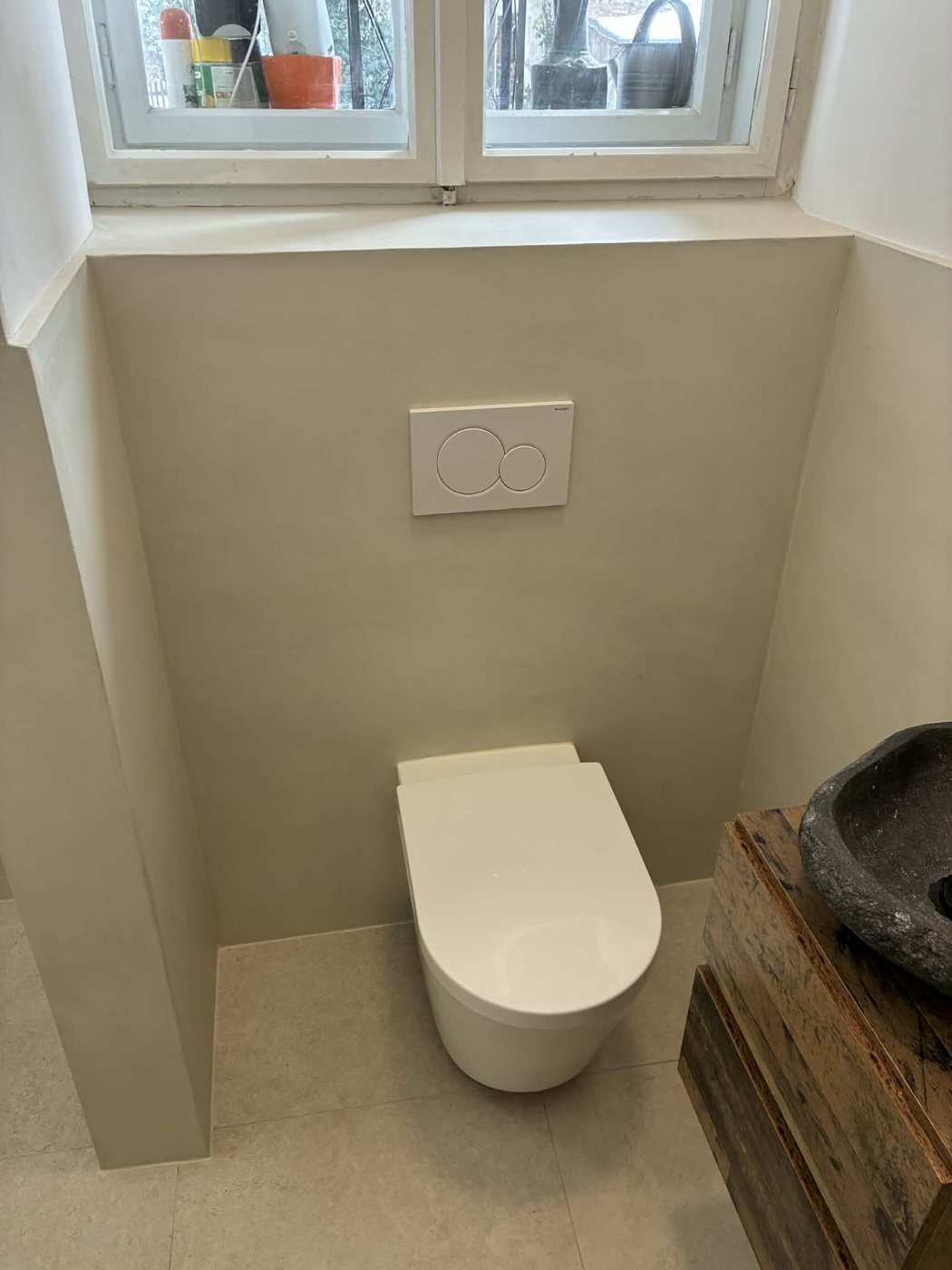 Dekor cement stena ob WC školjki in naravni kamniti umivalnik